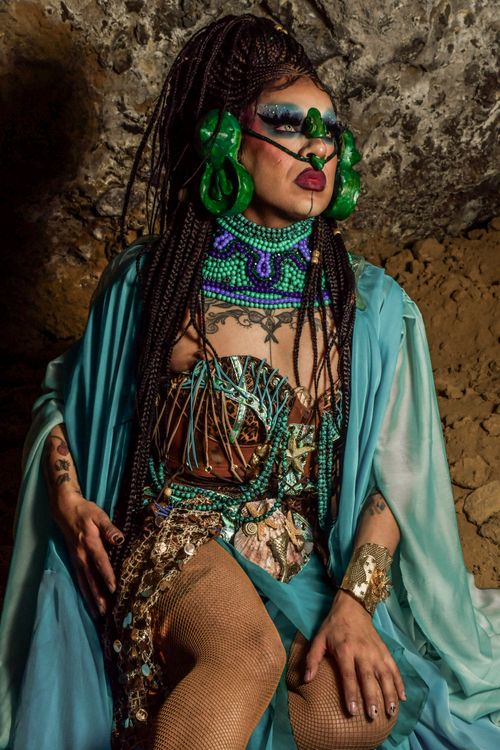 Free A dramatic portrait of a performer in a colorful, cultural costume inside a cave. Stock Photo