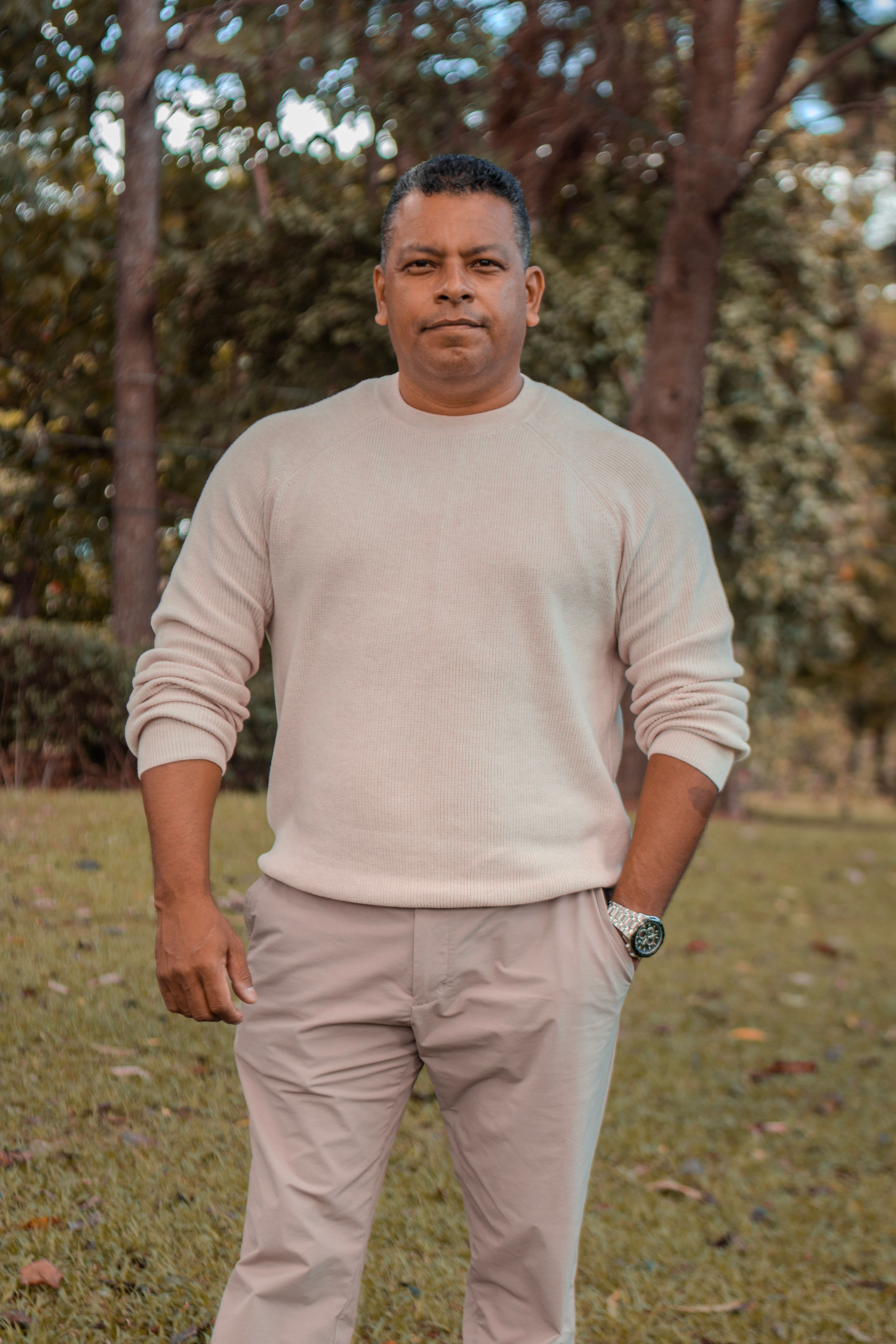 Portrait of a relaxed man in beige sweater standing outdoors.