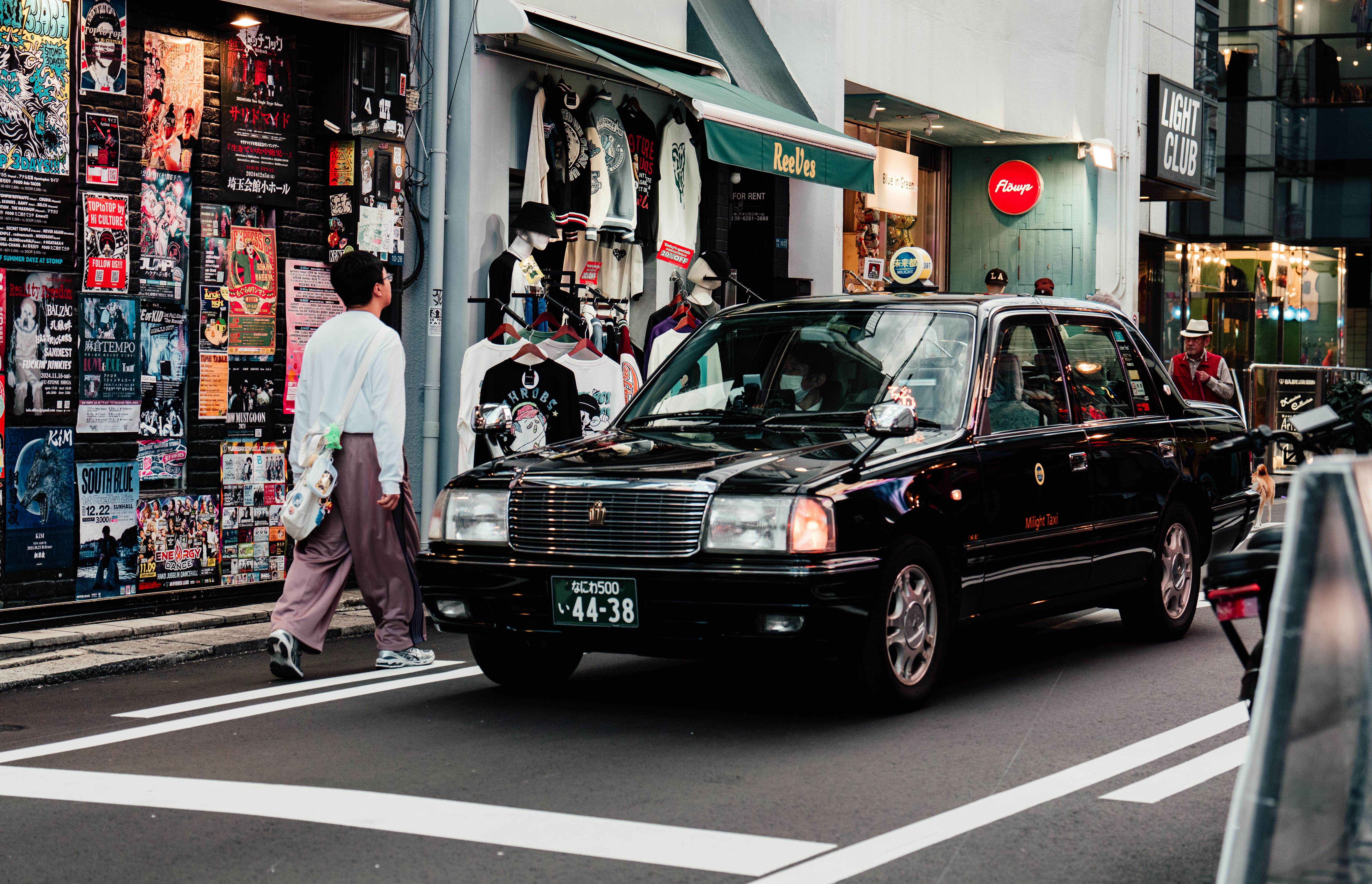 Vibrant street scene in downtown Osaka featuring a taxi and diverse storefronts.