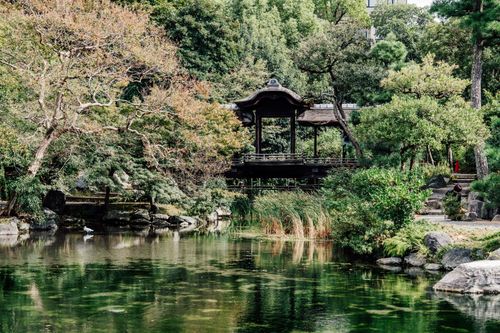 Free A tranquil Japanese garden featuring a traditional pavilion by the reflecting pond. Stock Photo