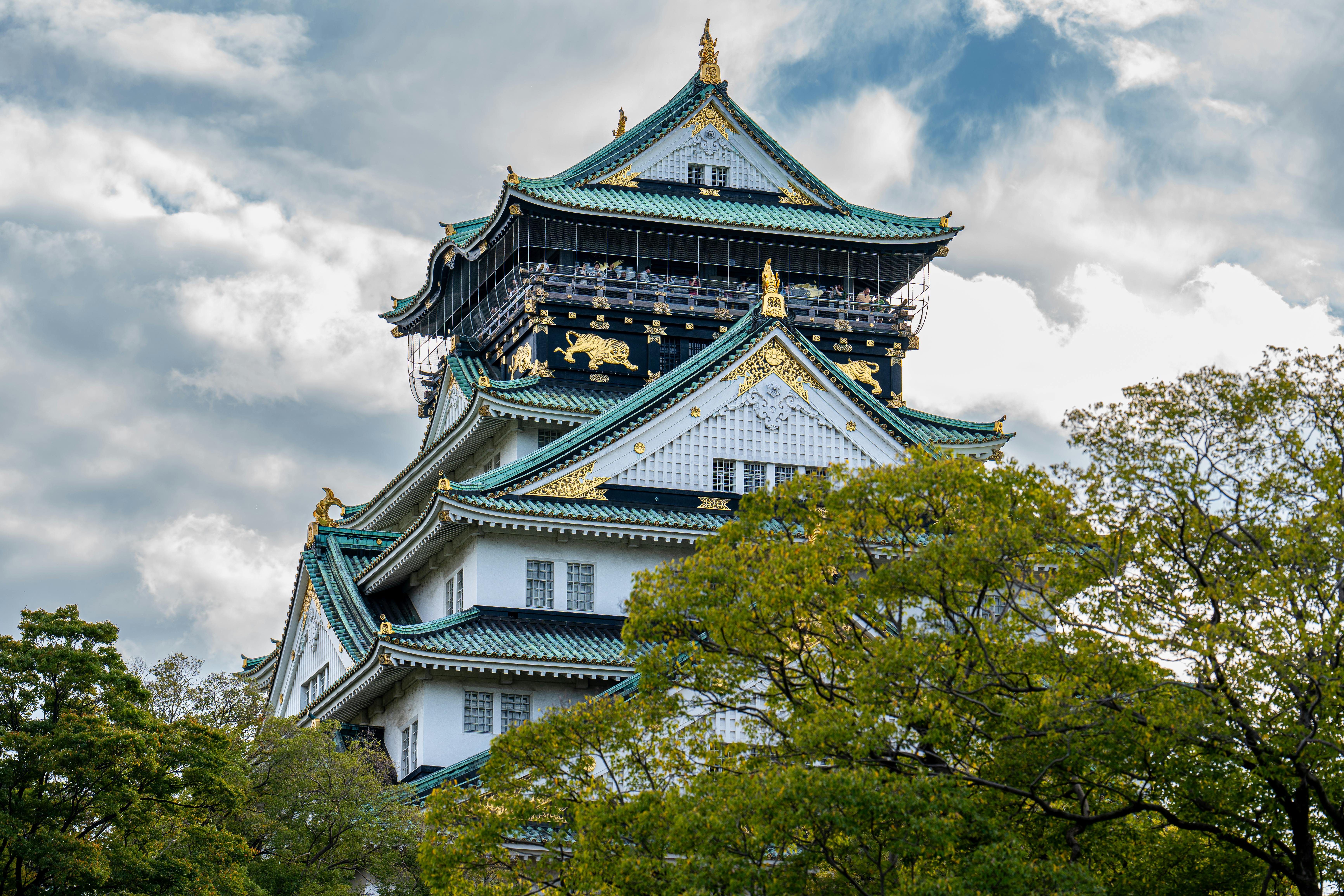 Explore the architectural beauty of Osaka Castle surrounded by lush greenery.