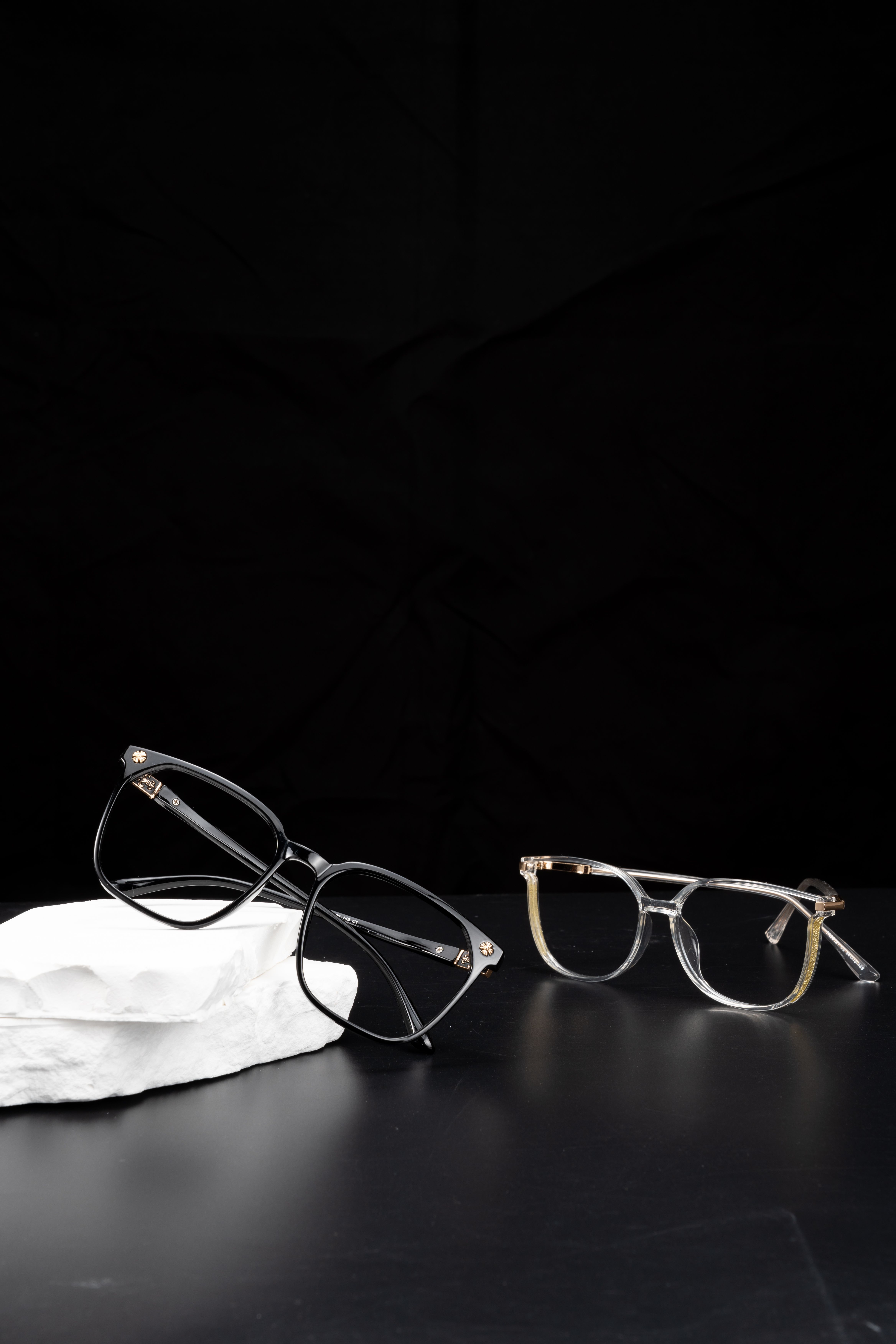 Stylish eyeglasses showcased on a dark surface against a black backdrop, perfect for fashion enthusiasts.