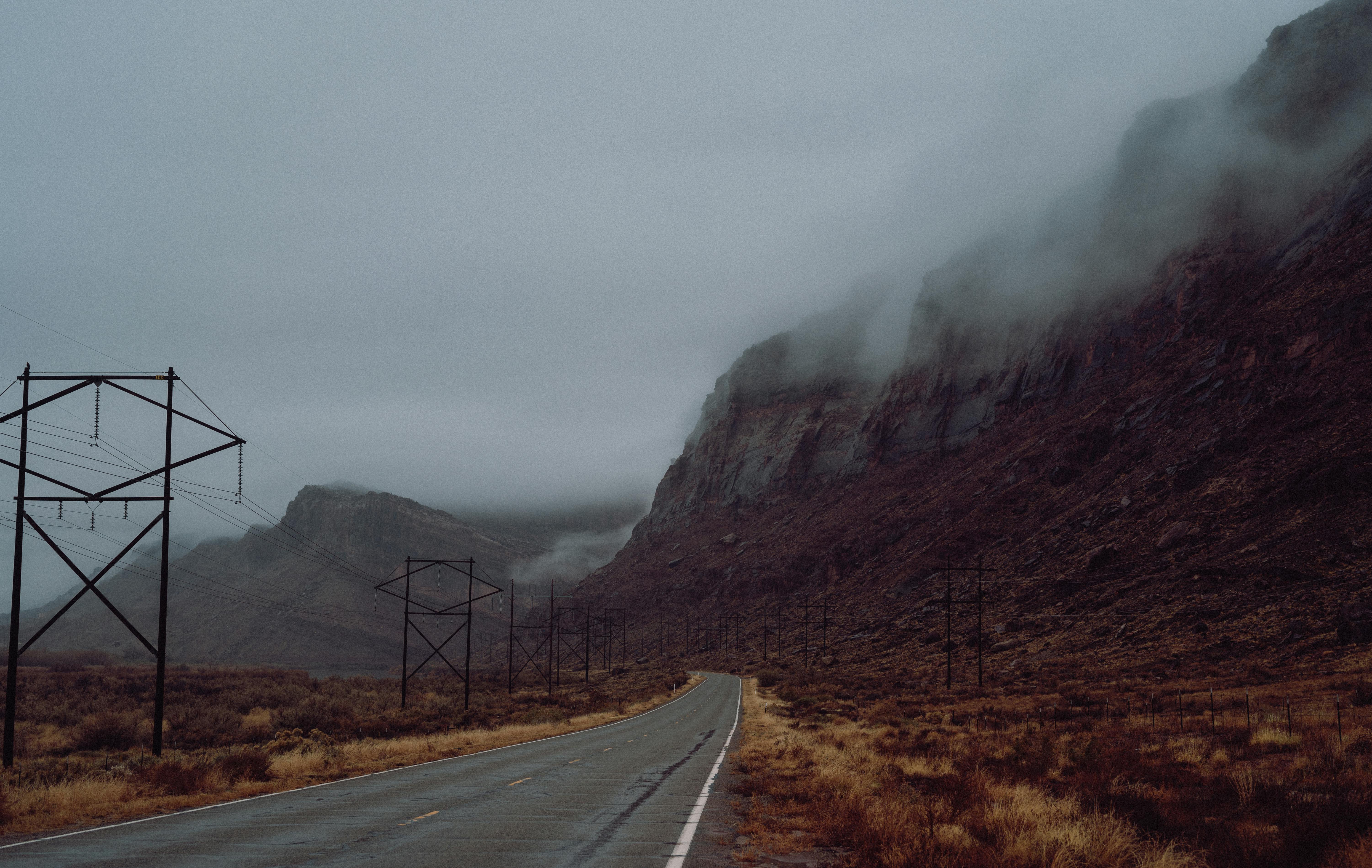 A misty road winding through rugged mountains, creating a mysterious, moody scene.