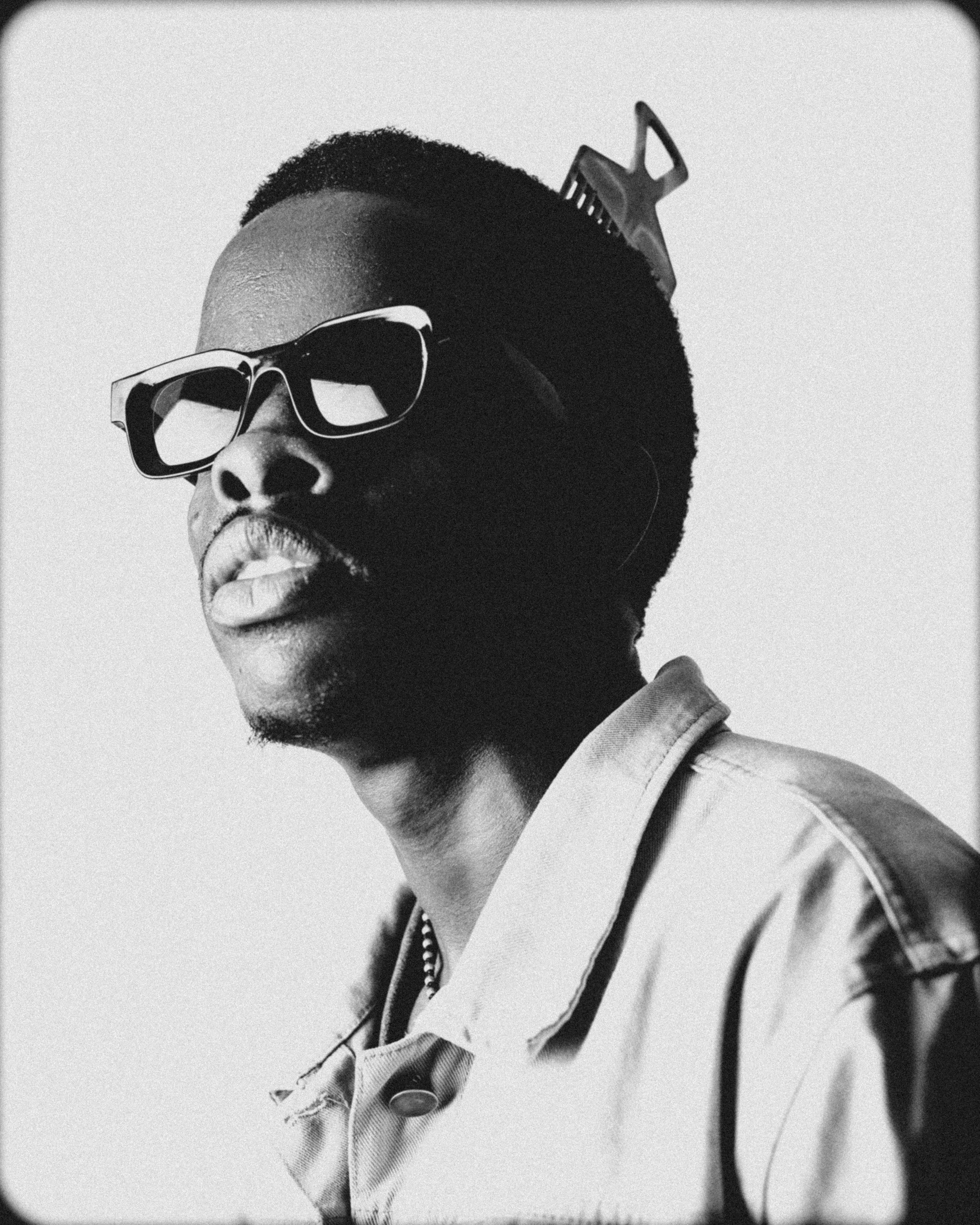 Artistic black and white portrait featuring a man in sunglasses with a unique hair accessory.
