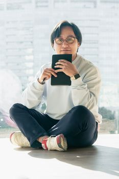 Person sitting cross-legged with a notebook, in a modern indoor space, relaxed atmosphere.