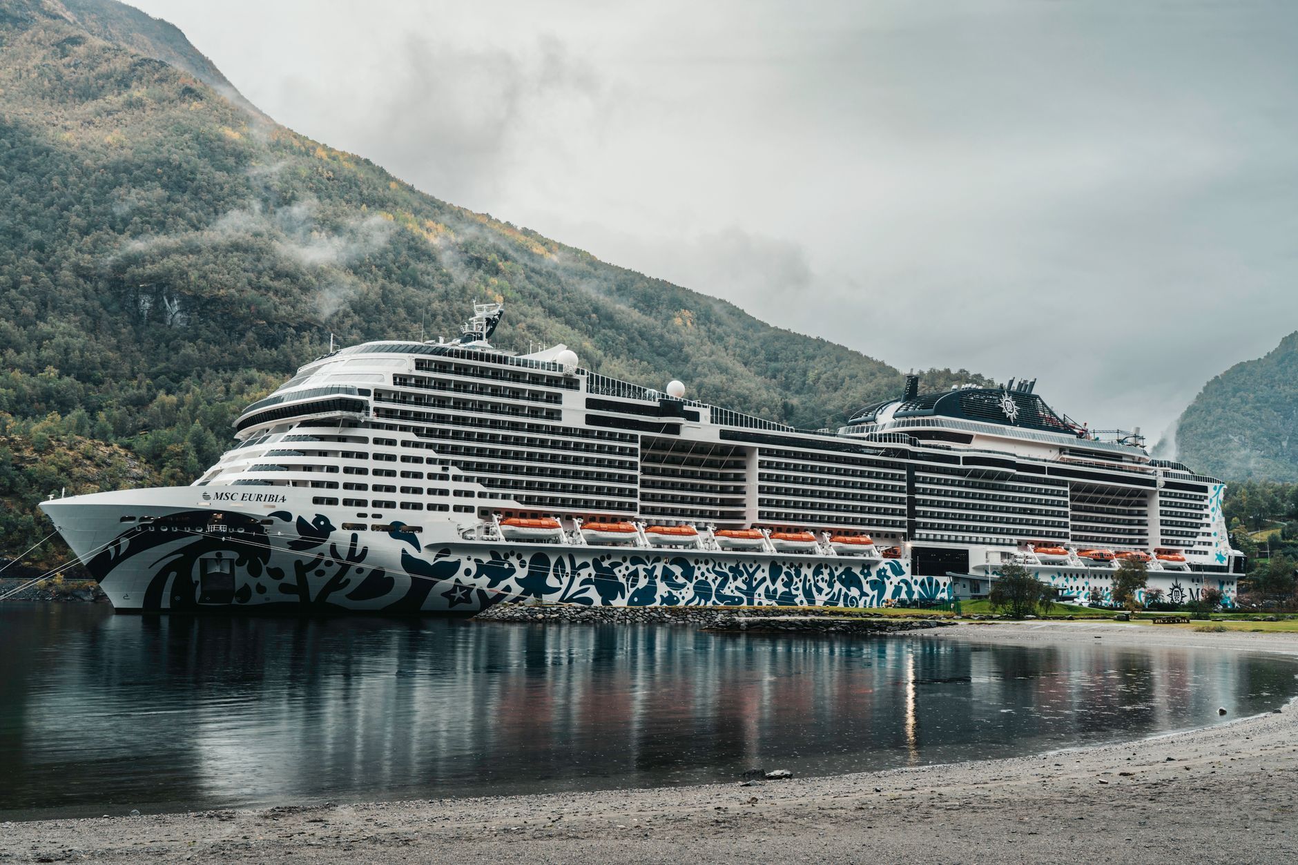 Kreuzfahrtschiff, das in einem malerischen norwegischen Fjord umgeben von Bergen angedockt ist.