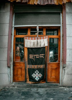 Capture of a rustic wooden Tibetan door adorned with a traditional fabric drape, showcasing intricate patterns.