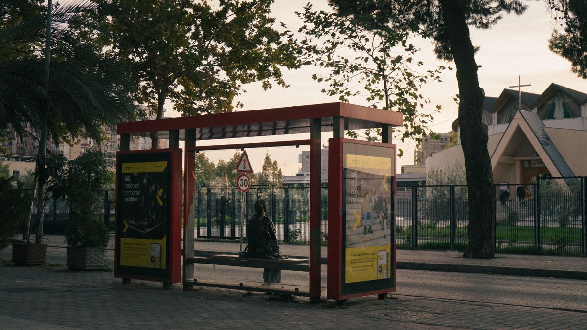 A person waiting at a bus shelter in Tirana, Albania