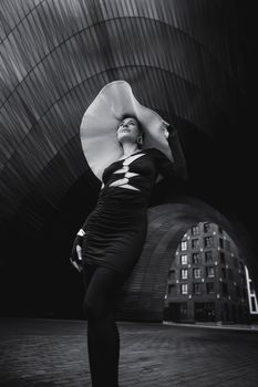 Striking black and white portrait of a woman in a modern urban environment, exuding elegance and style.