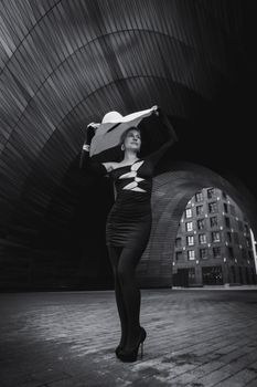 Elegant woman posing elegantly in a modern urban environment under a striking archway.