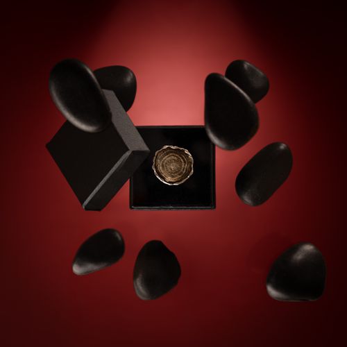 Free Elegant black gift box surrounded by floating stones on a rich red background. Stock Photo