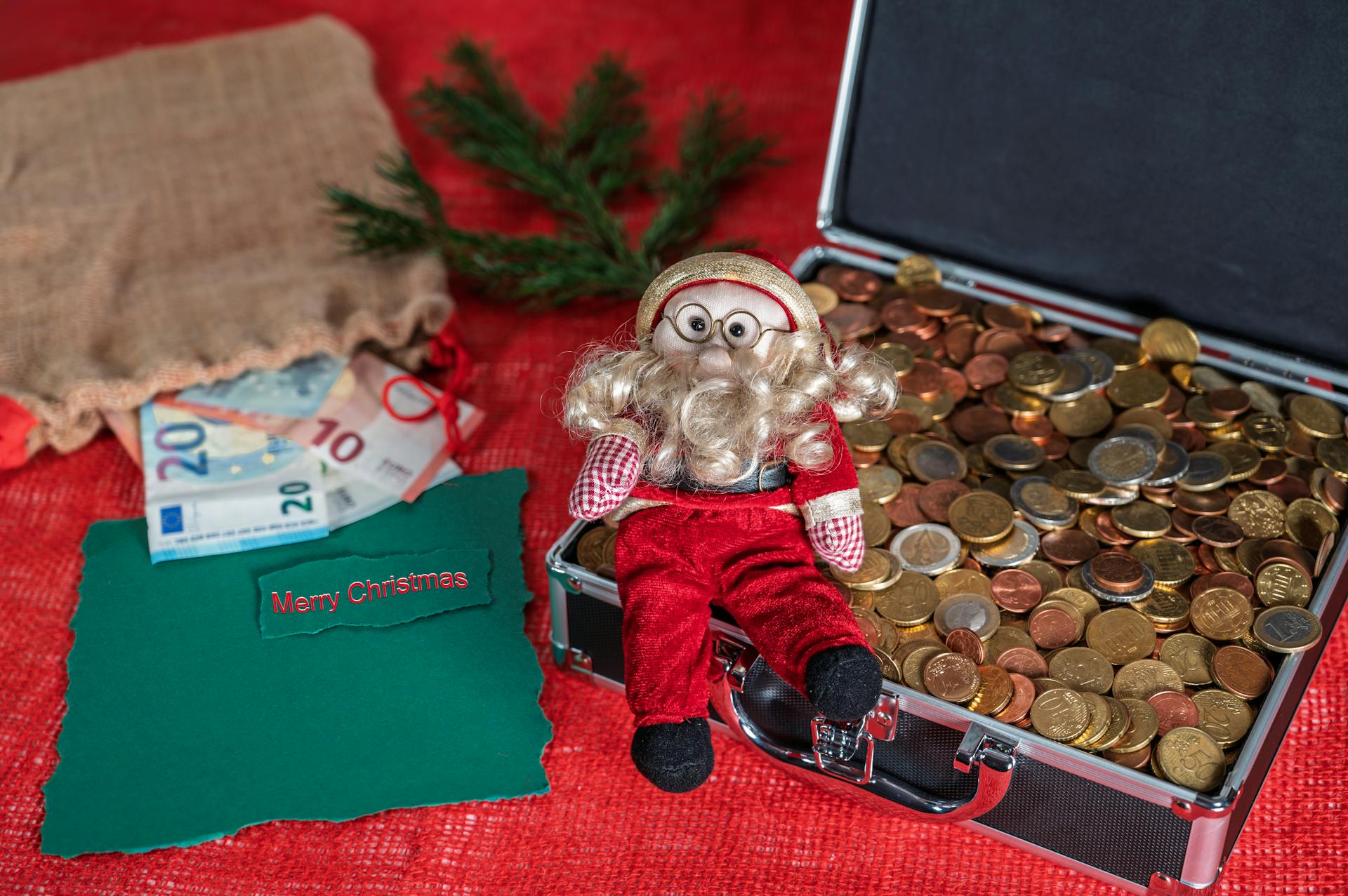 Santa figurine with euro coins and a Merry Christmas card create a festive holiday scene.