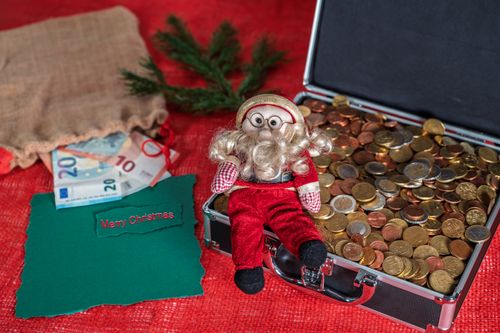Free Santa figurine with euro coins and a Merry Christmas card create a festive holiday scene. Stock Photo