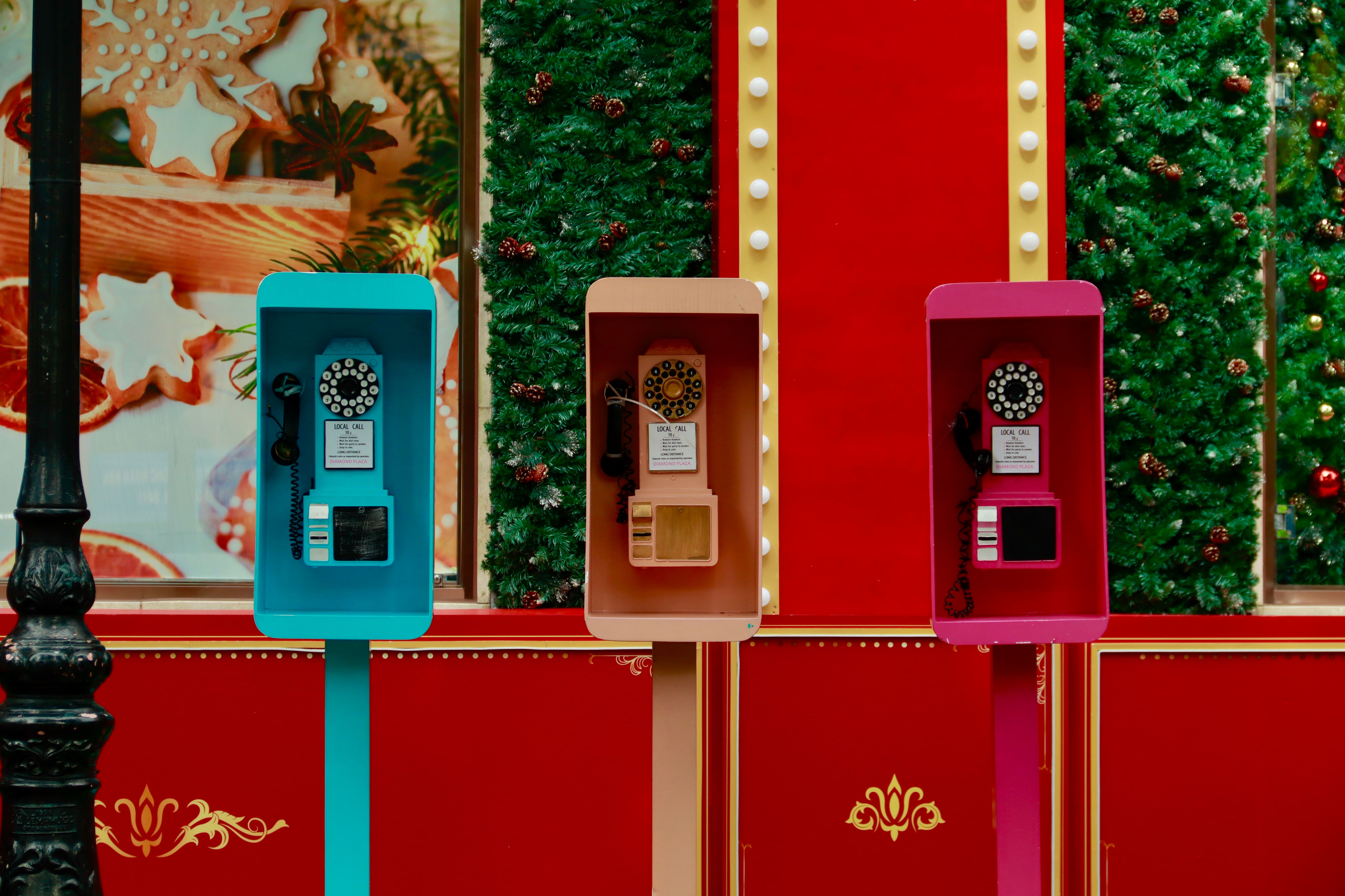 Three vintage phone booths with holiday decor on a festive street.