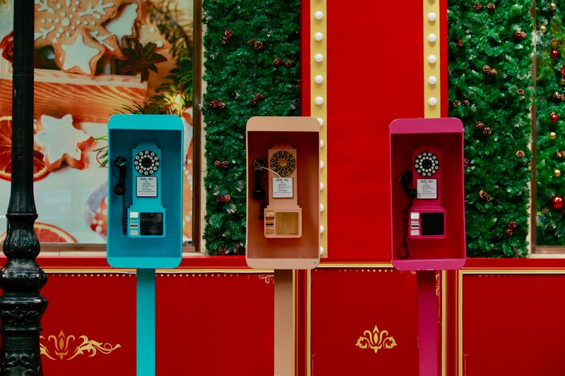 Three vintage phone booths with holiday decor on a festive street.