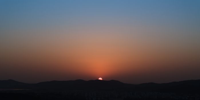 A scenic sunset over the mountains in Wuxi, highlighting the changing sky colors.