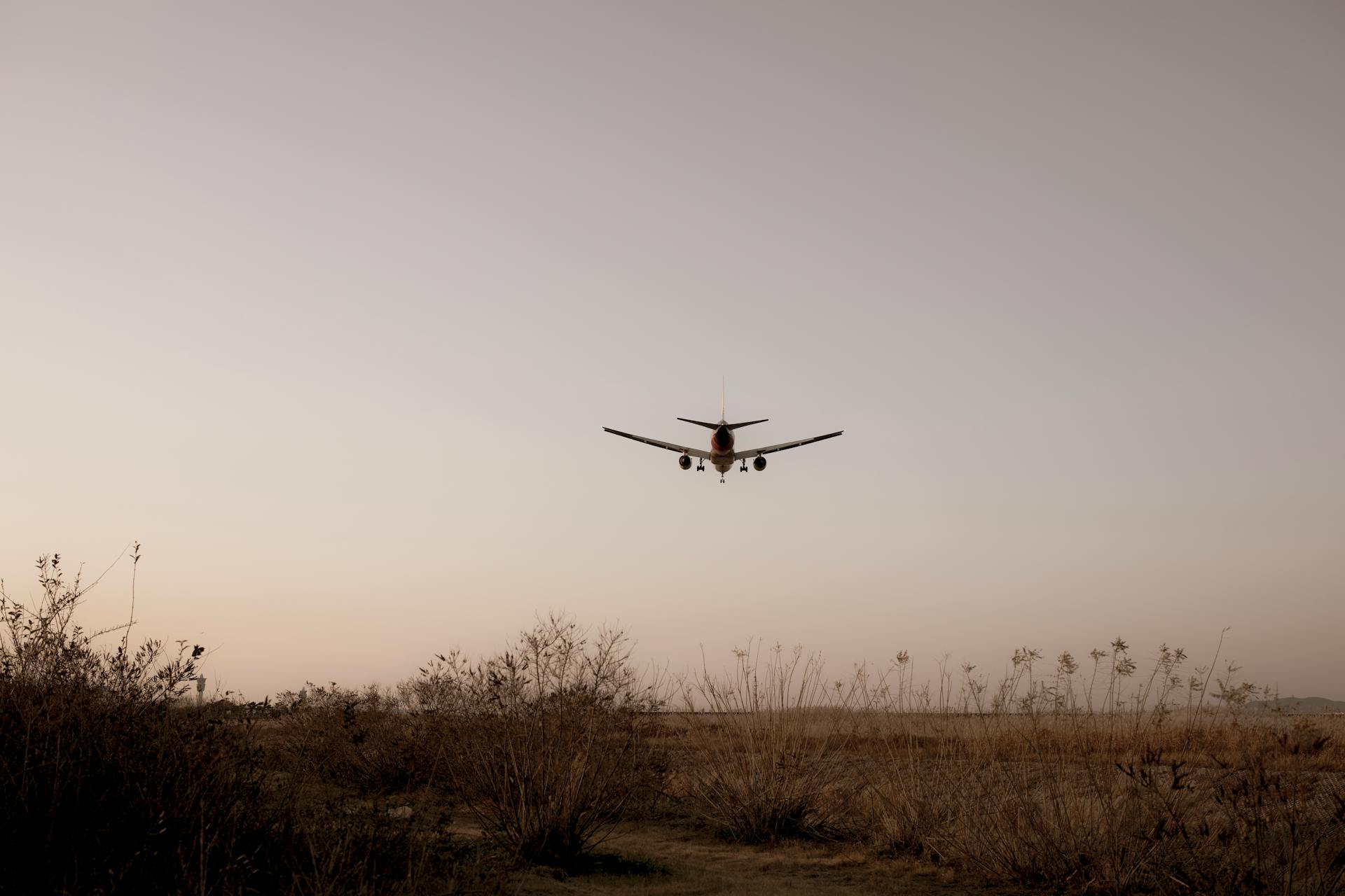 An airplane approaching for landing over a grassy field at sunset, signifying travel and adventure.