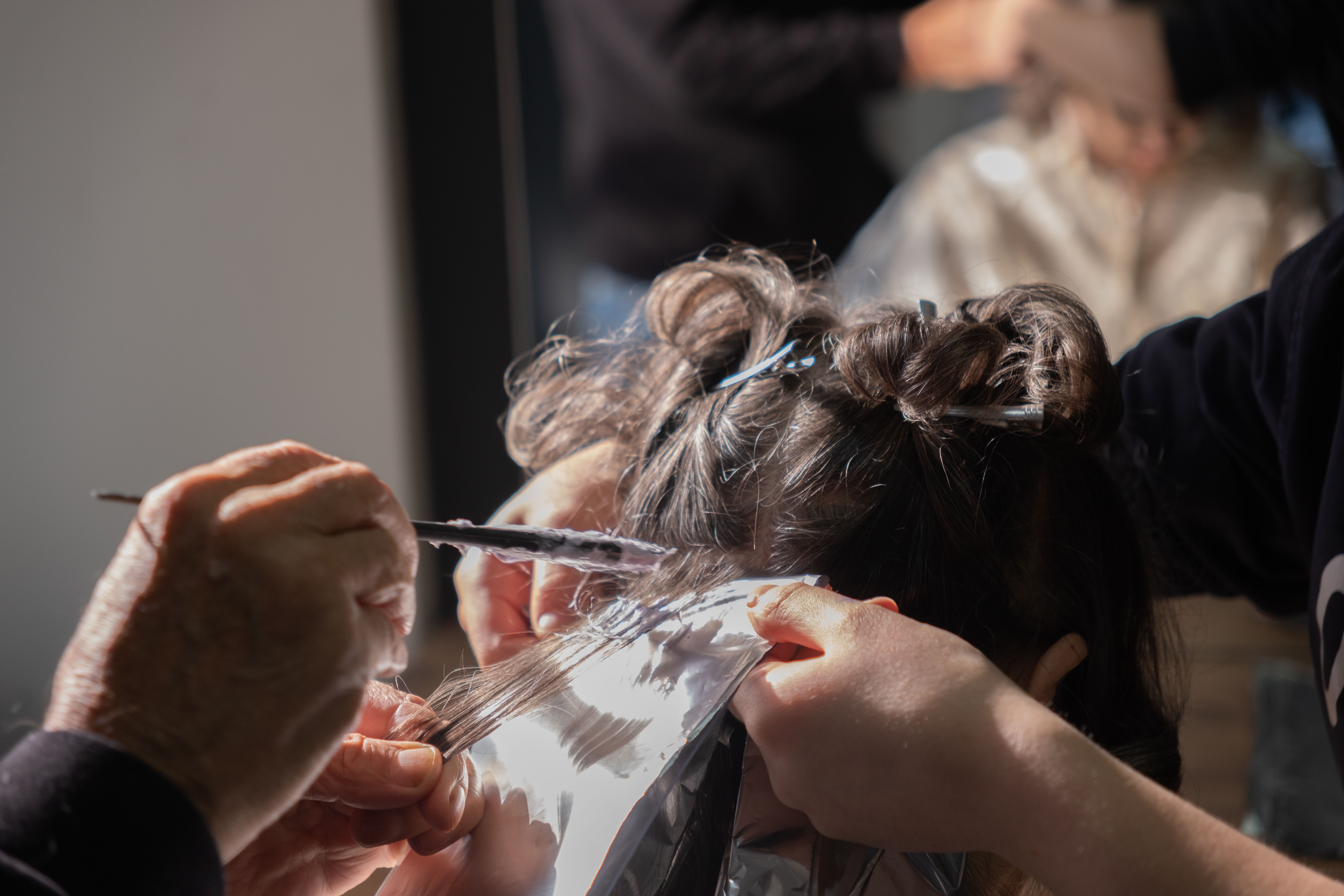 Hairdresser applying foil highlights to client's hair in a salon.