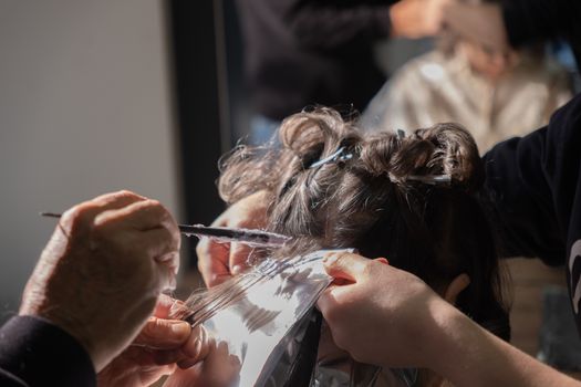 Hairdresser applying foil highlights to client's hair in a salon.