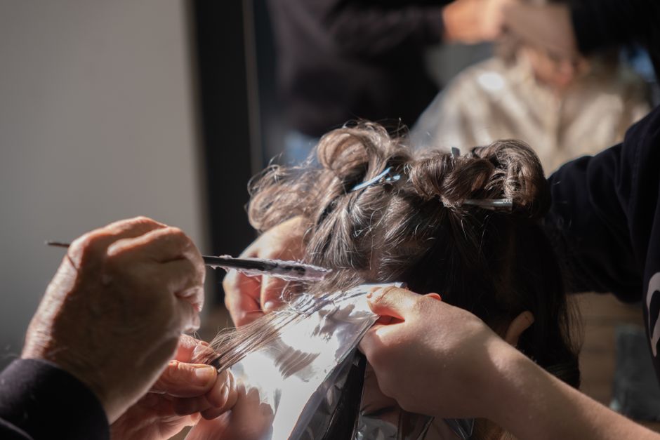 Hairdresser applying foil highlights to client's hair in a salon.