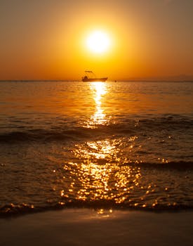 A breathtaking sunset with a boat silhouetted against the golden waters of Balıkesir, Türkiye.