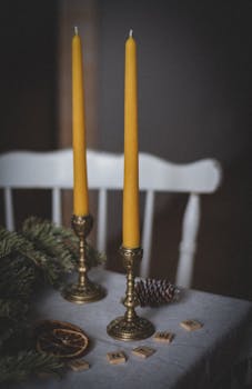 Tall beeswax candles and rustic winter decorations on a table create a warm holiday ambiance.