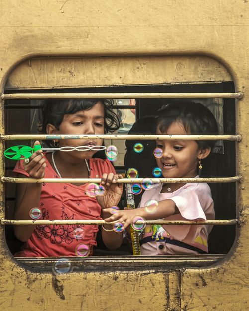 Free Two cheerful children enjoying bubbles through a train window, capturing innocence and joy. Stock Photo