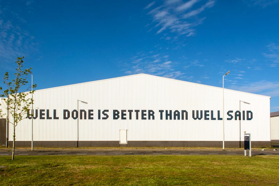 Large industrial building featuring an inspiring quote in bold letters, under a clear blue sky.
