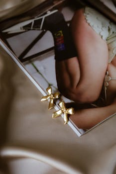 Stylish gold bow earrings placed on an open fashion magazine, showcasing chic style.