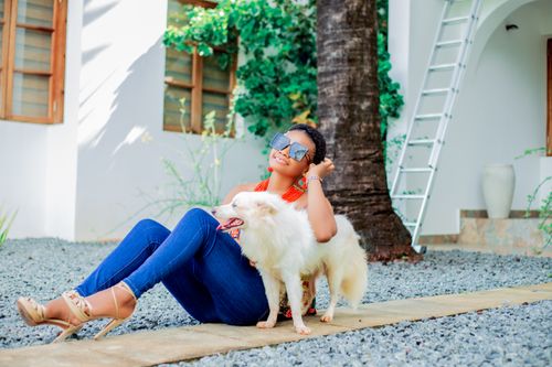 Free Woman enjoying a sunny day with her dog, sitting outdoors by a palm tree. Stock Photo