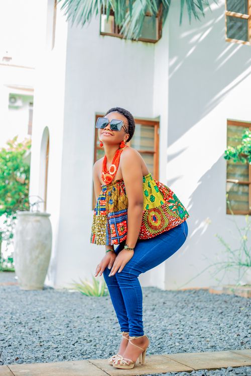 Free Young woman poses in colorful African print top and heels outdoors. Stock Photo
