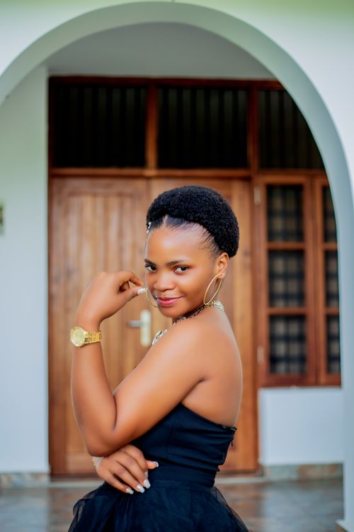 Free Confident young woman in a black dress posing happily outdoors. Stock Photo