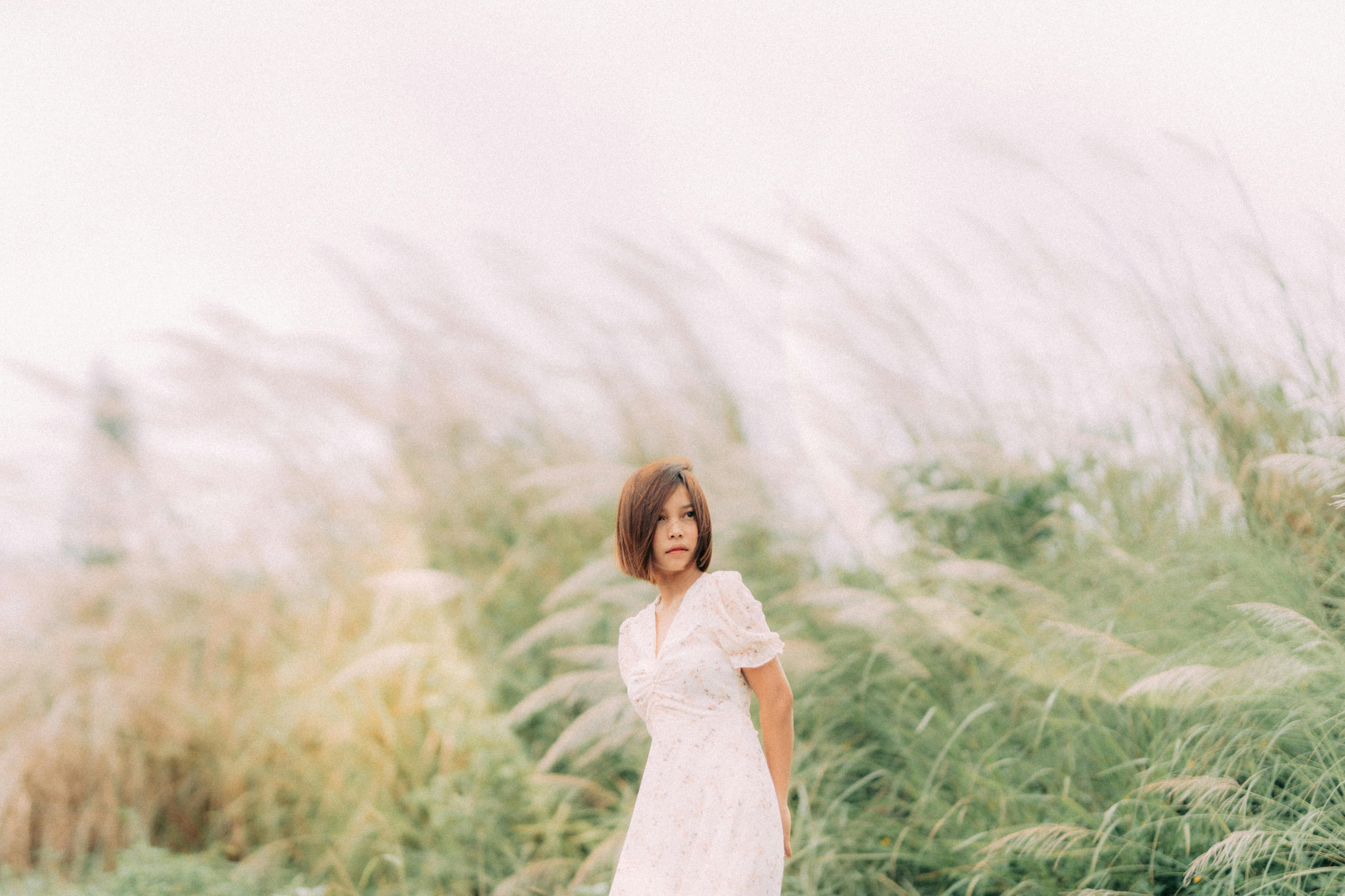 A serene portrait of an adult woman in a grassy outdoor setting, evoking a sense of calm and nature.