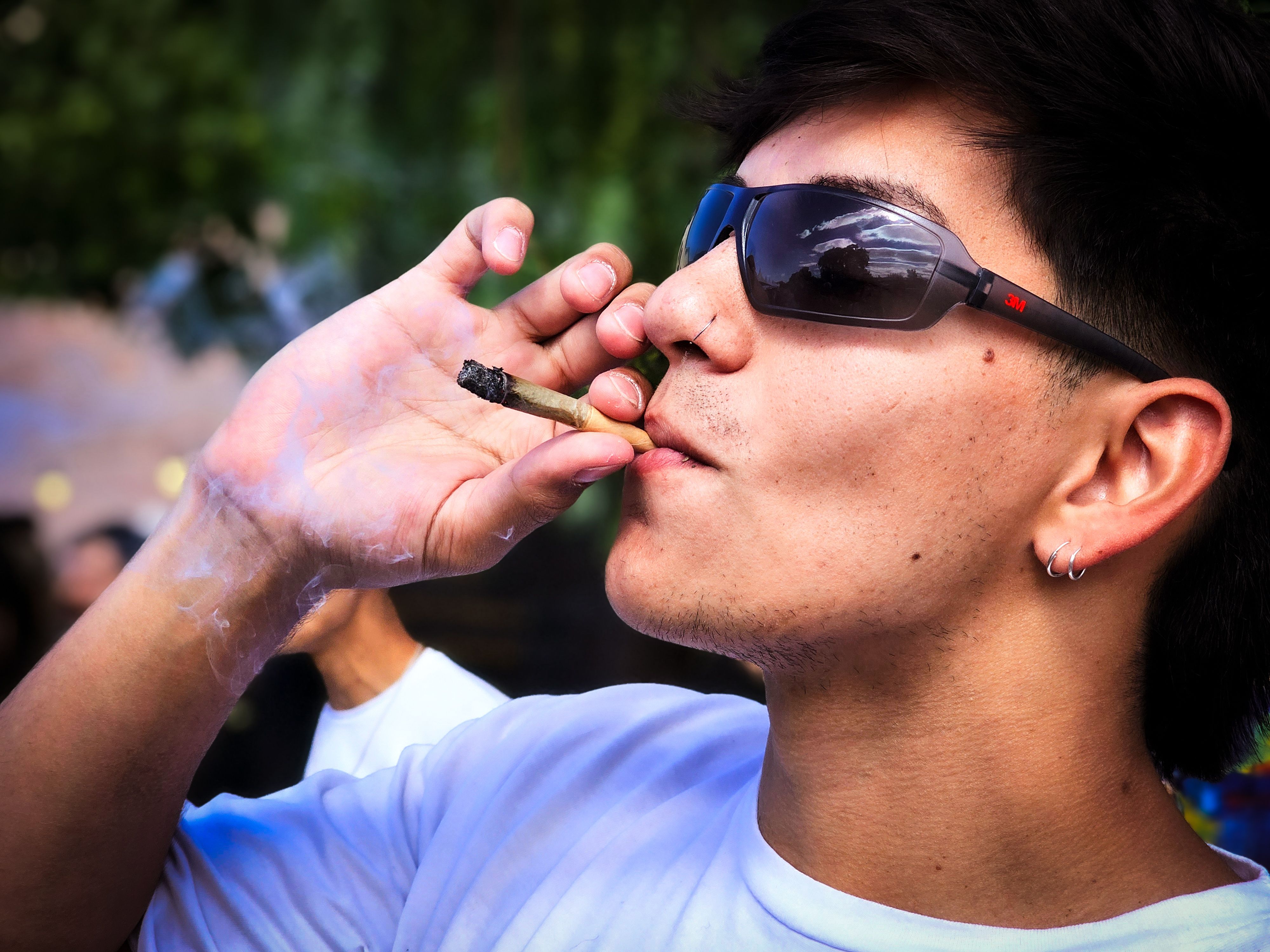 Joven Fumando Al Aire Libre Con Gafas De Sol · Foto de stock gratuita