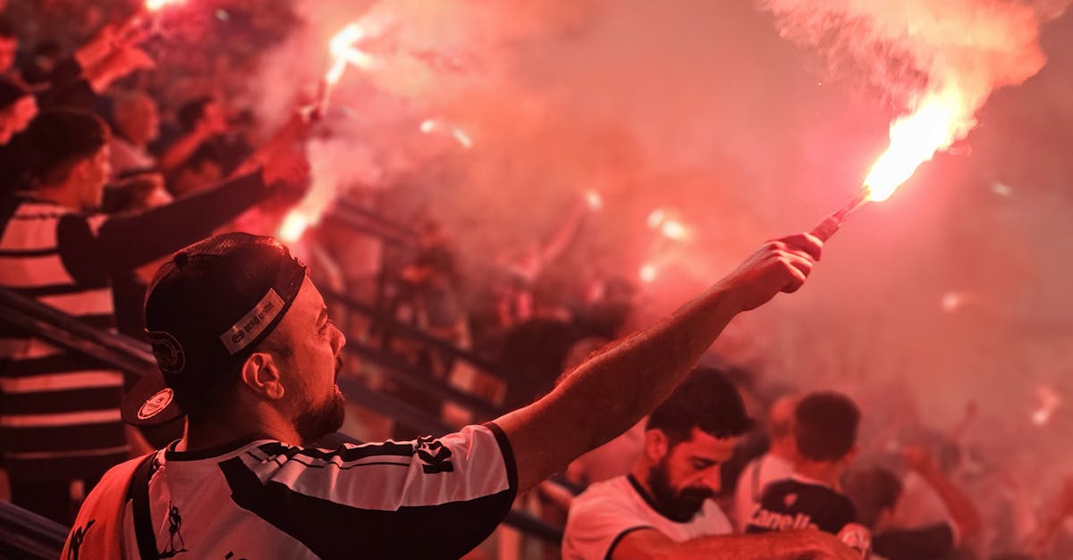 Energetic crowd celebrating with red flares at a sports event, creating a vibrant and passionate atmosphere.