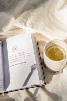 Open book with inspiring quote and lemon tea in sunlight, evoking a peaceful morning feel.