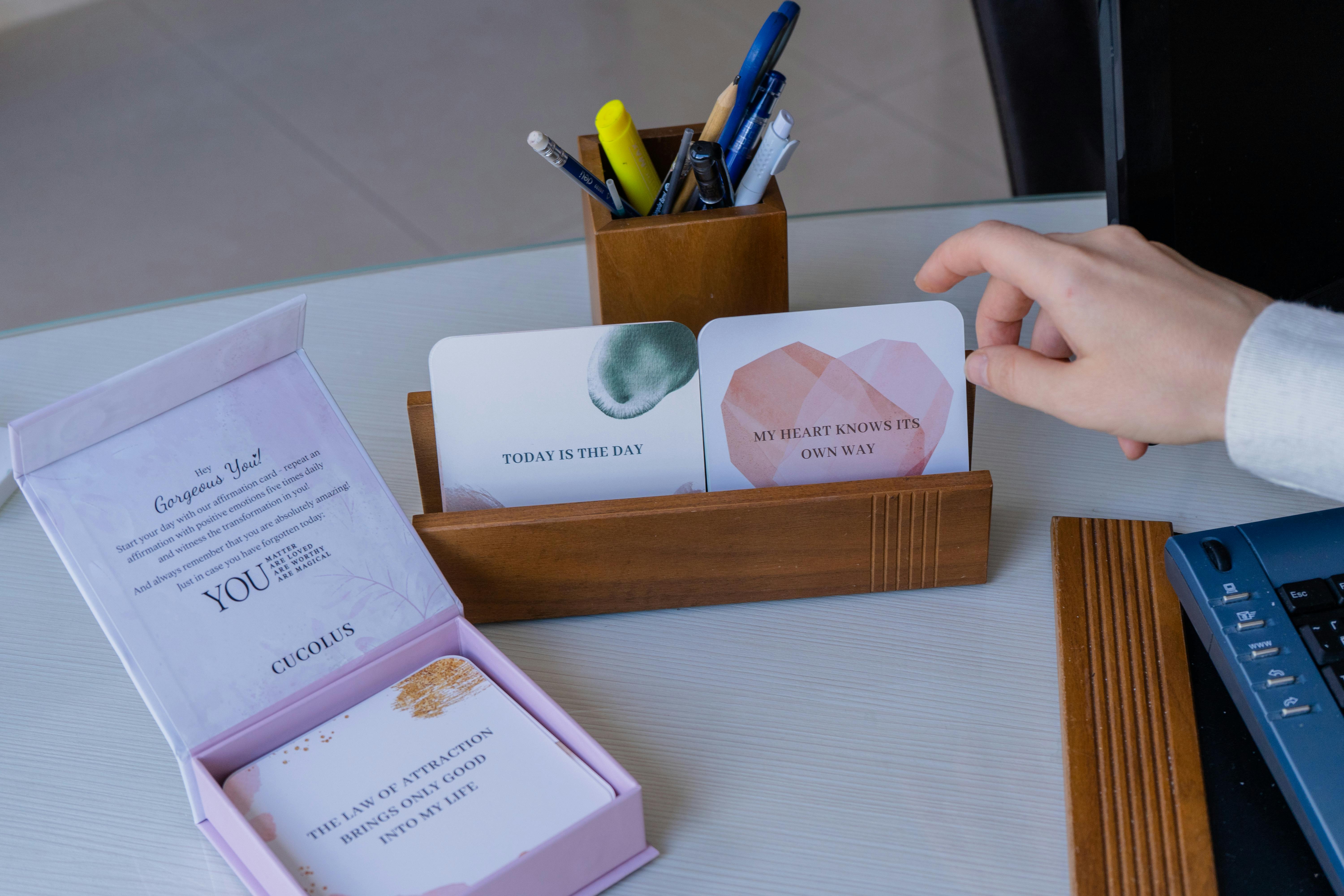 Free A hand interacting with motivational cards on a desk, creating a positive and inspiring workspace setup. Stock Photo