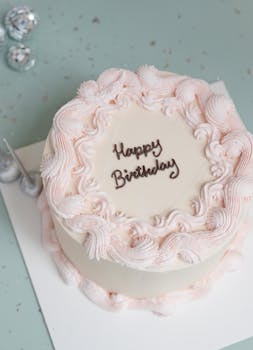 Top view of a white birthday cake with pink frosting decorations and 'Happy Birthday' text.