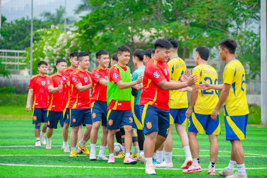 Two youth soccer teams exchange high-fives after a match on an outdoor field.