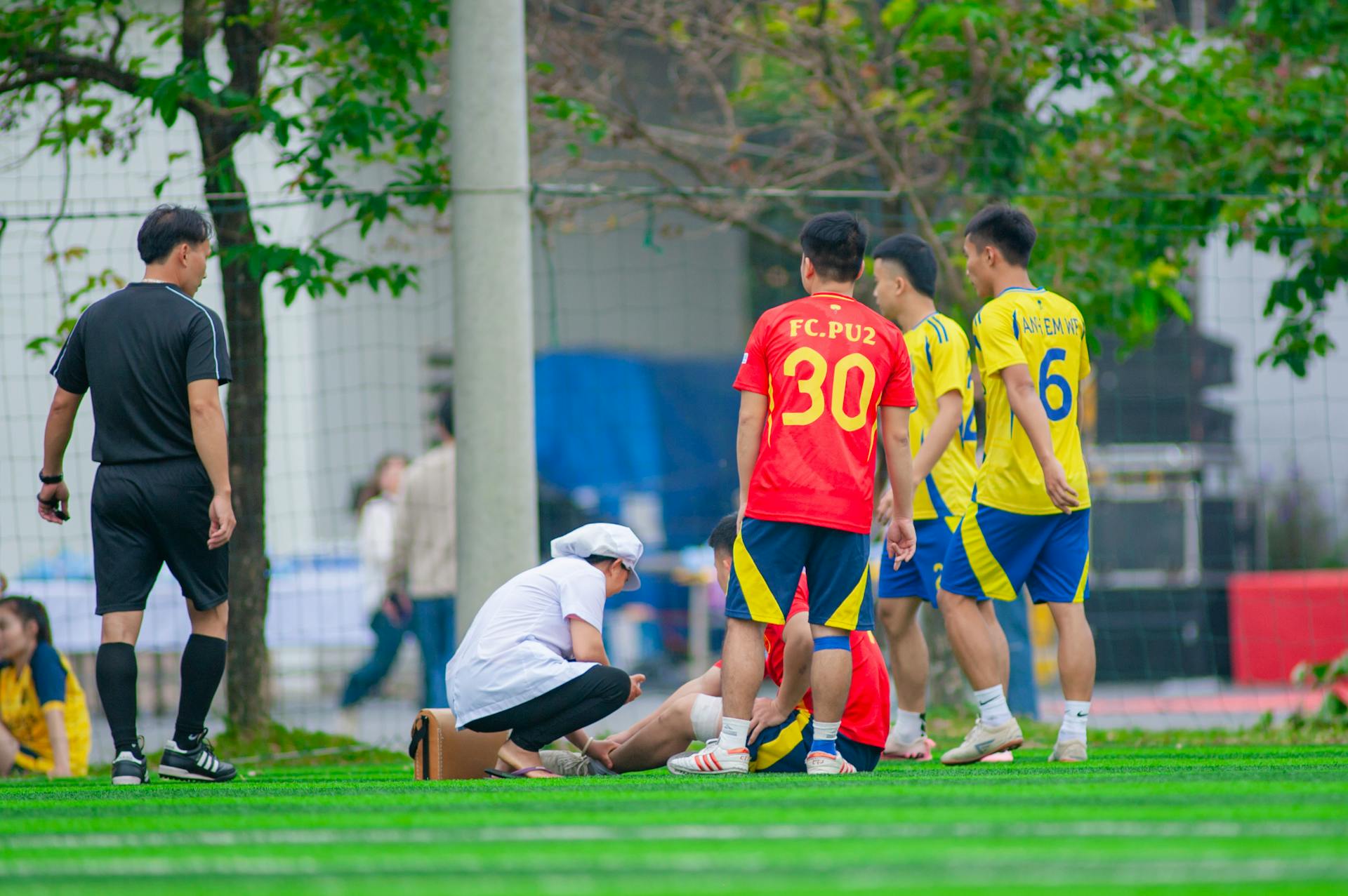 Youth soccer players and medical staff attend to an injury on the field in Hanoi, Vietnam.