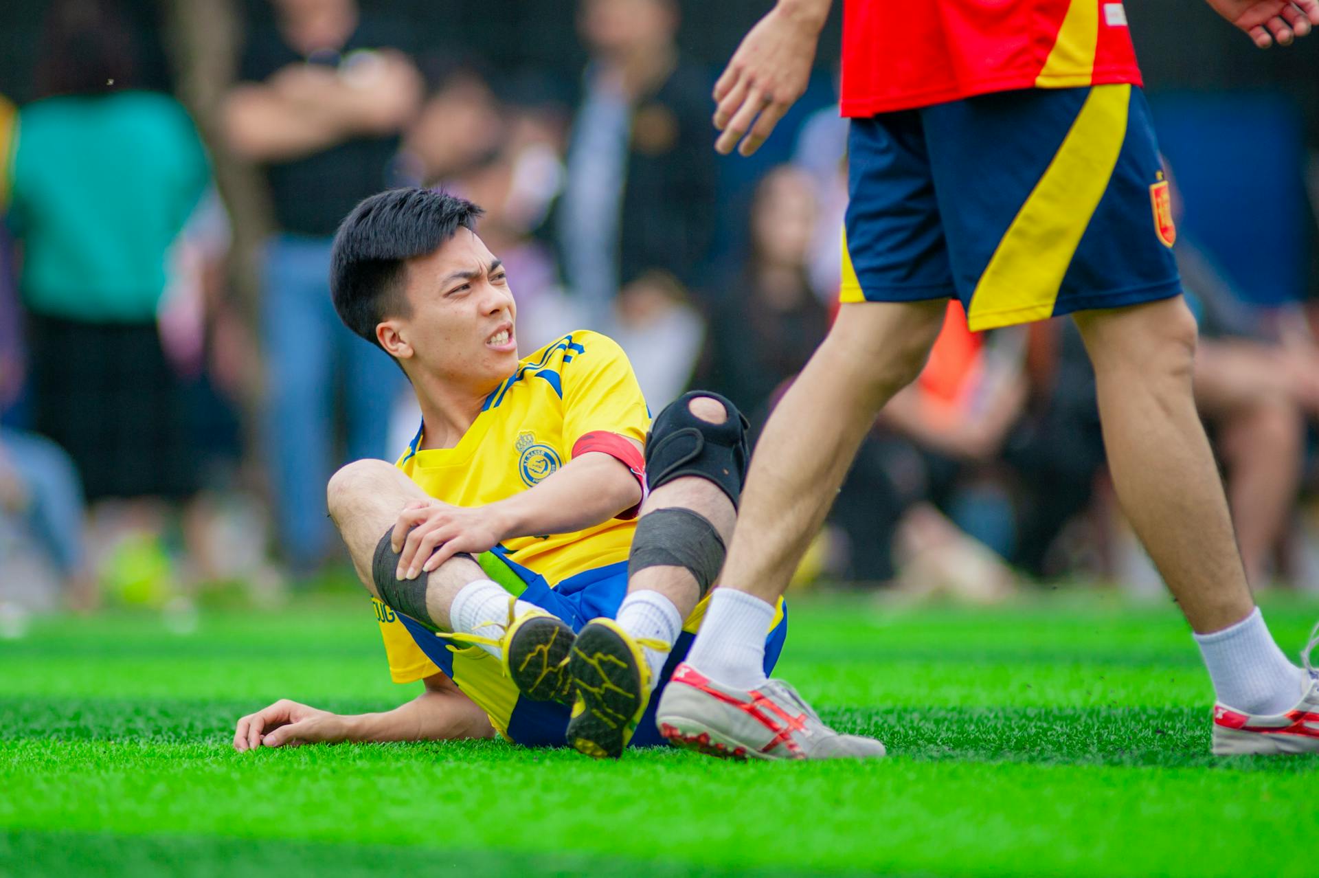 Soccer player on ground with knee injury during match.