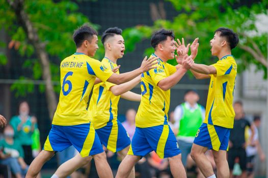 A local soccer team celebrates a goal in Hà Nội, Vietnam, amidst a vibrant outdoor setting.