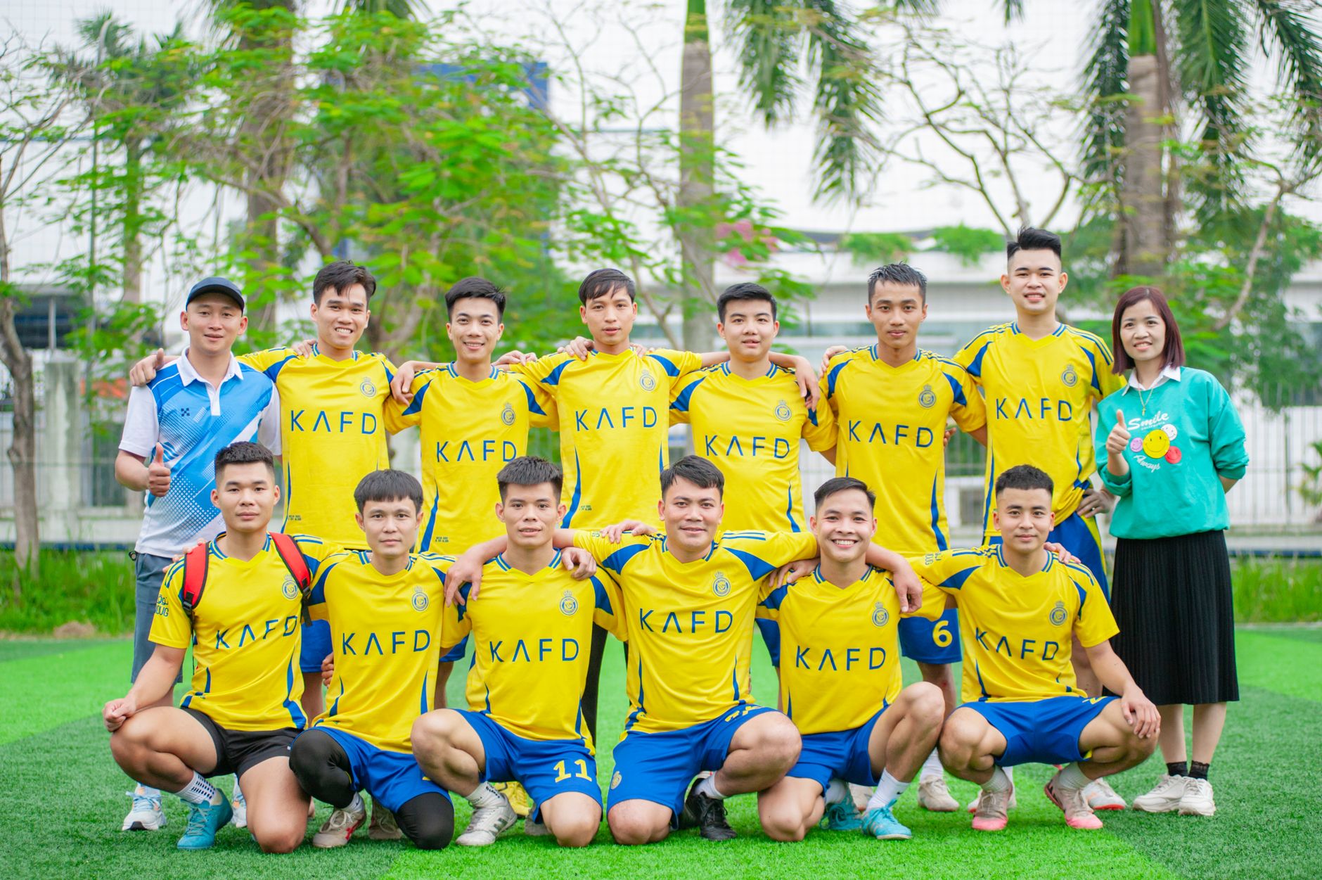 Group photo of a Vietnamese soccer team in yellow uniforms outdoors.