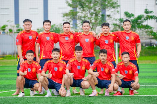 A soccer team in red jerseys posing on a green field in Hanoi, Vietnam.