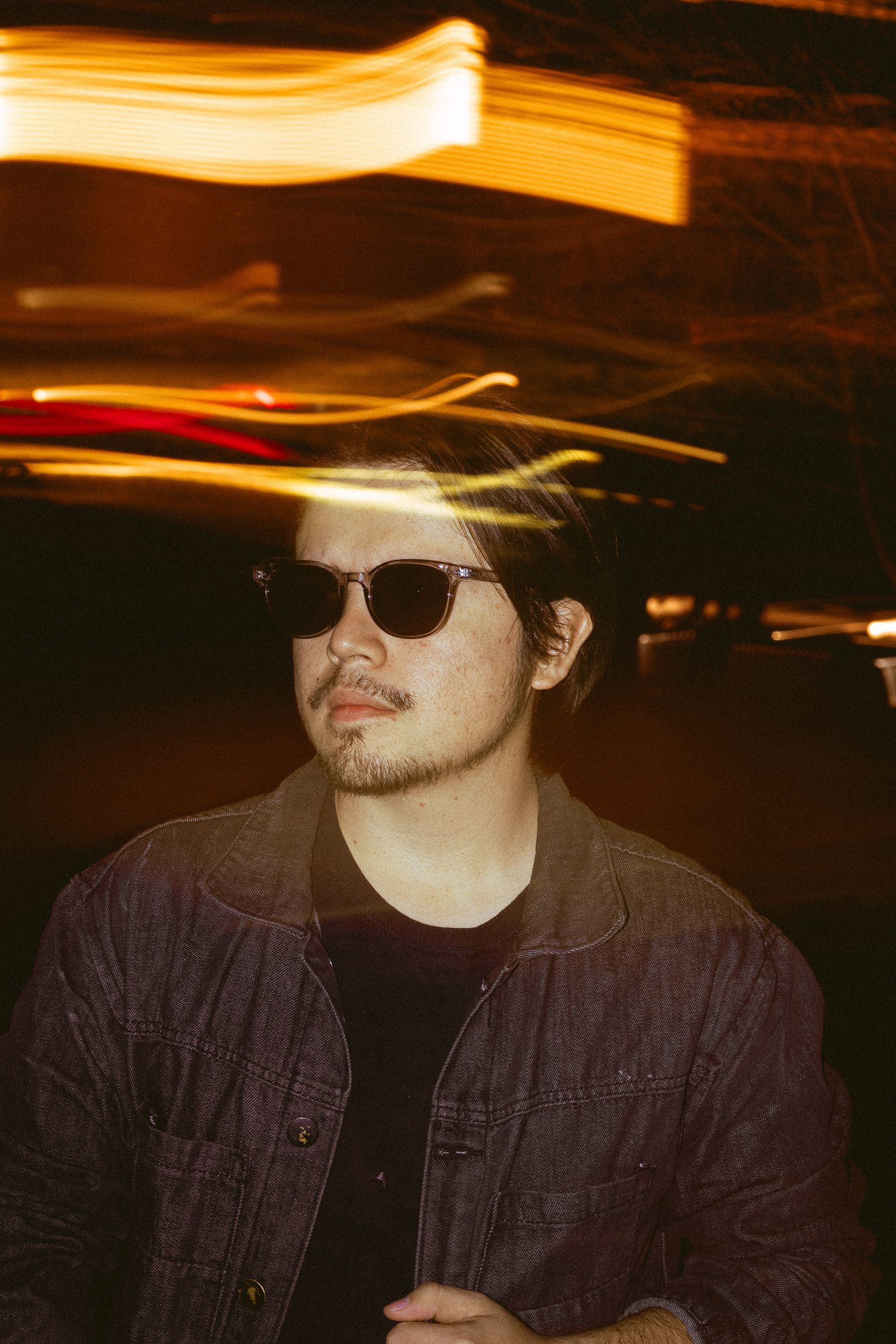 Portrait of a young man with sunglasses and light trails at night.