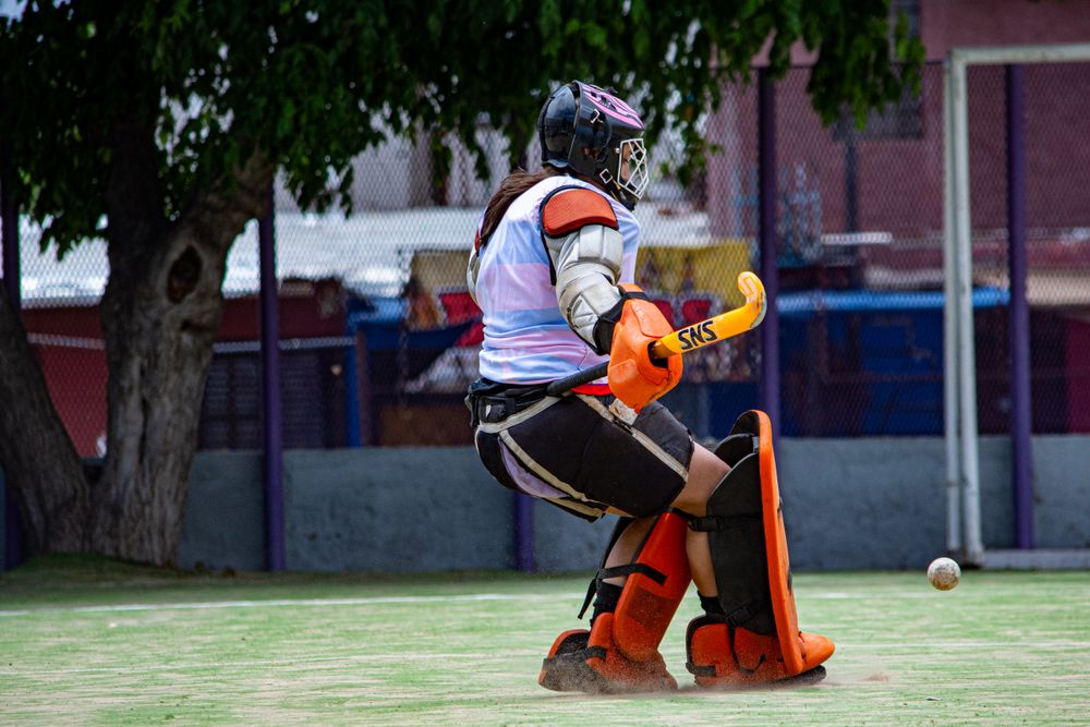 Field hockey goalkeeper in protective equipment and team jersey during a match