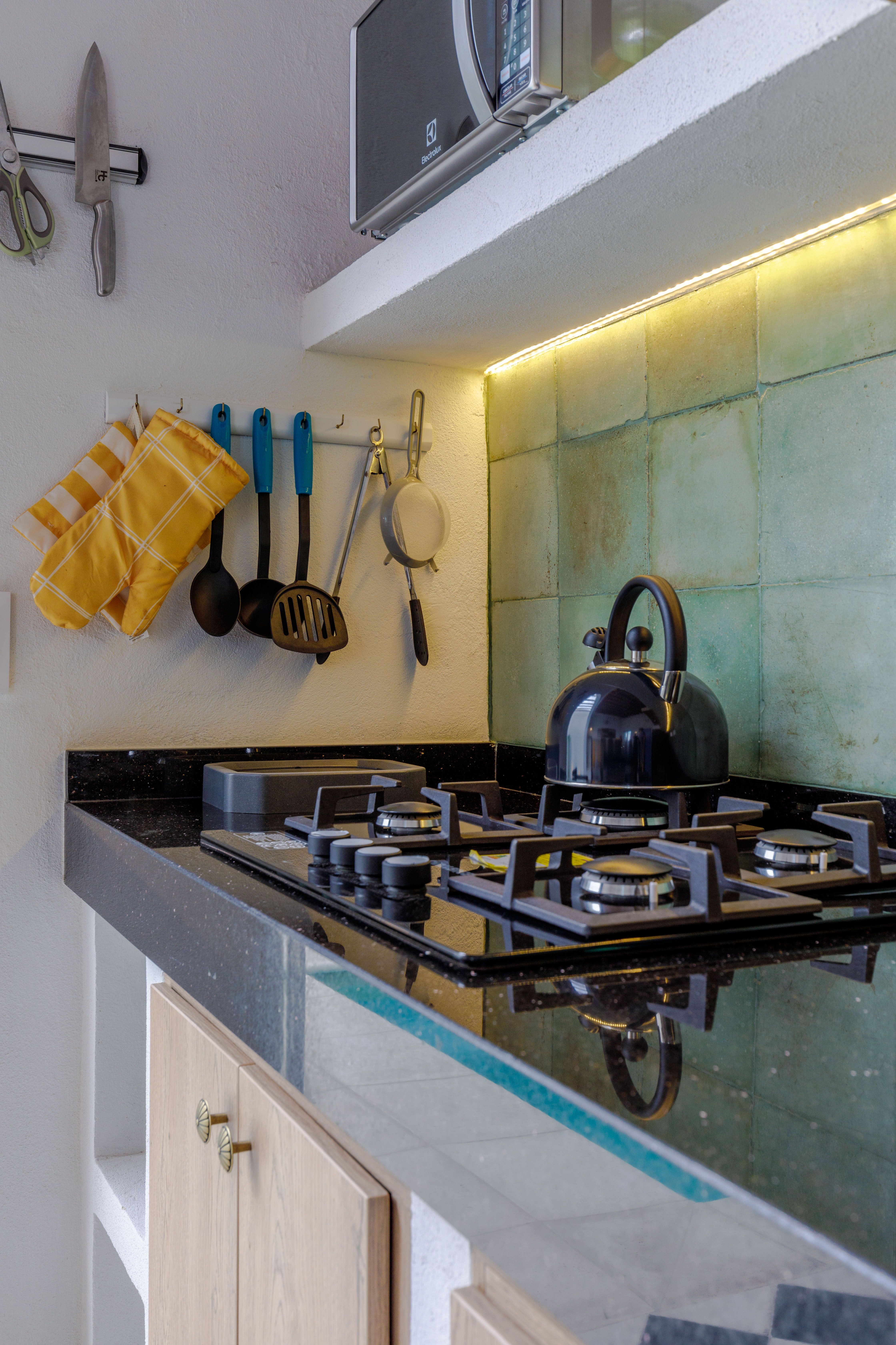 A stylish kitchen corner equipped with a gas stove and hanging utensils—or perhaps a photograph of knives hanging on the wall.