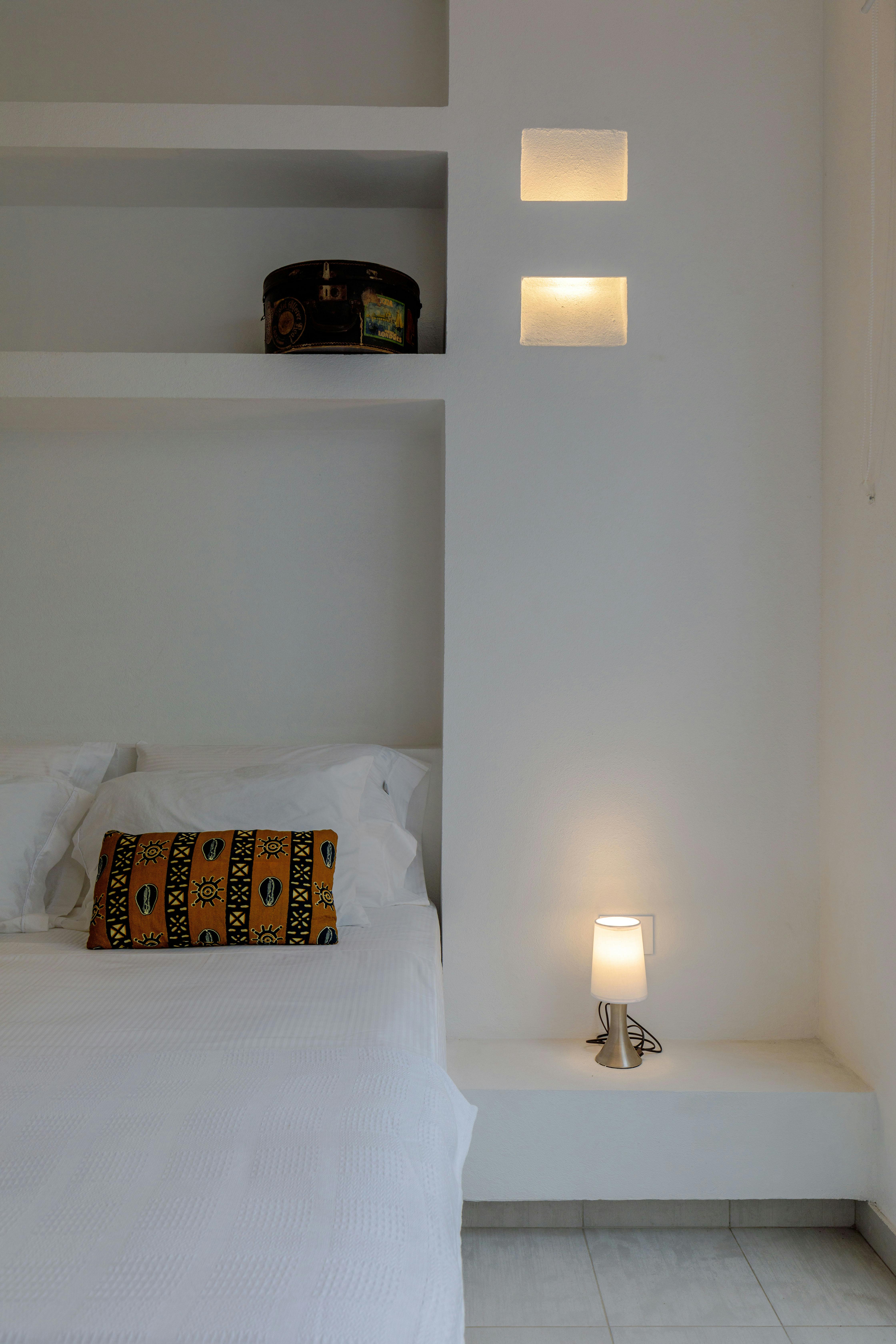 A serene, minimalist bedroom interior with white walls and cozy decor.