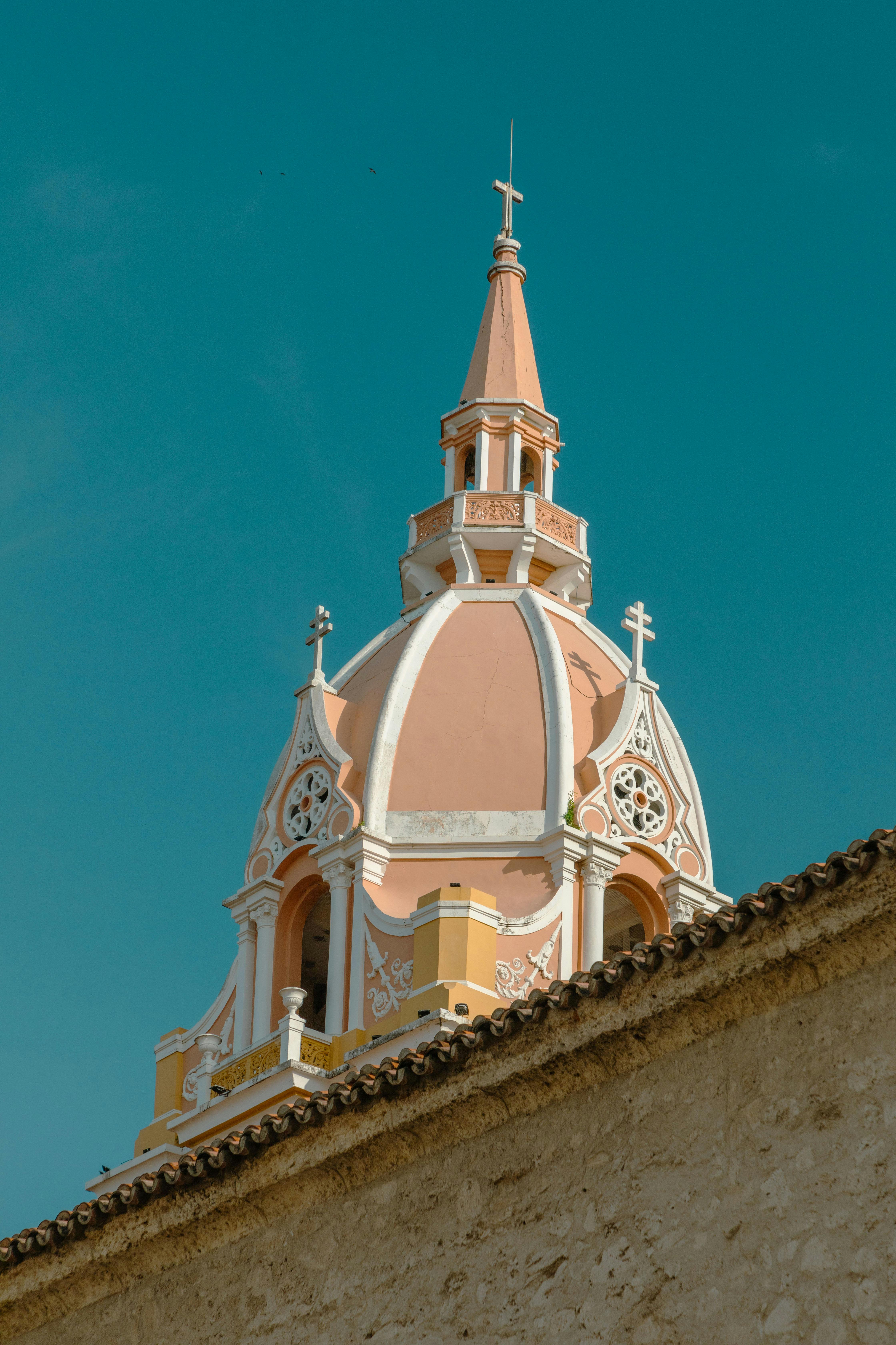 Photograph of a historic pink and white dome with intricate design against a clear blue sky.