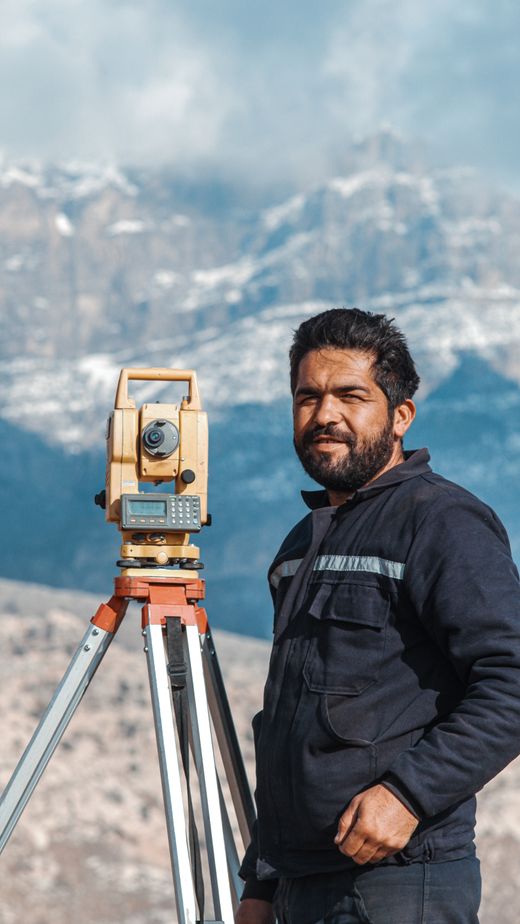 A surveyor beside a theodolite on a hillside — photo by Ferhat Kocakaya on Pexels